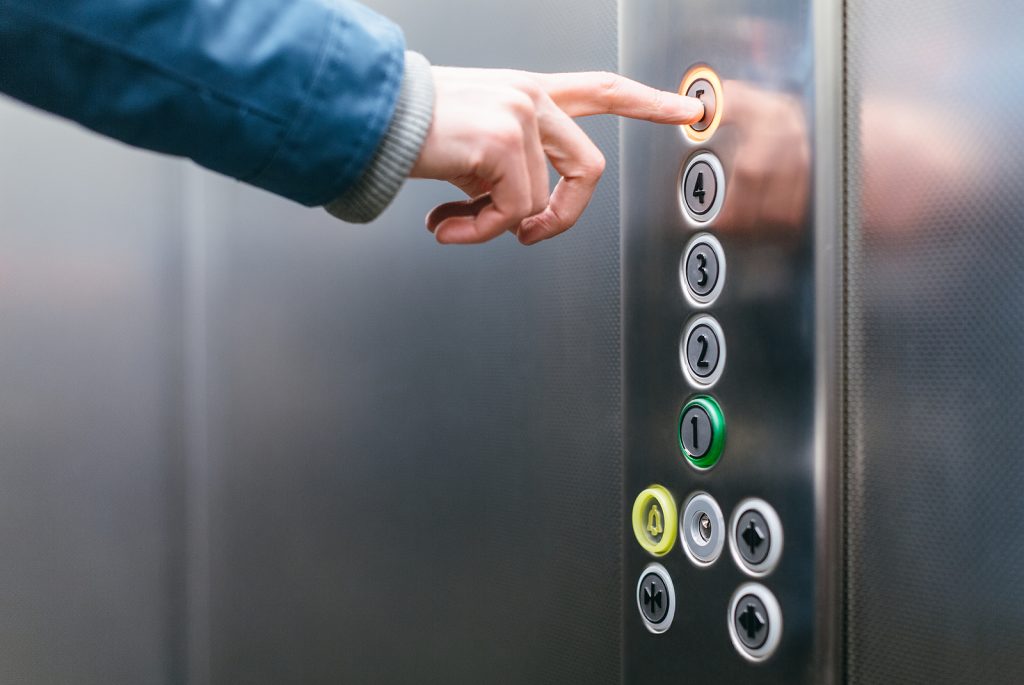 Passenger lift - man pressing the fifth floor button in the elevator